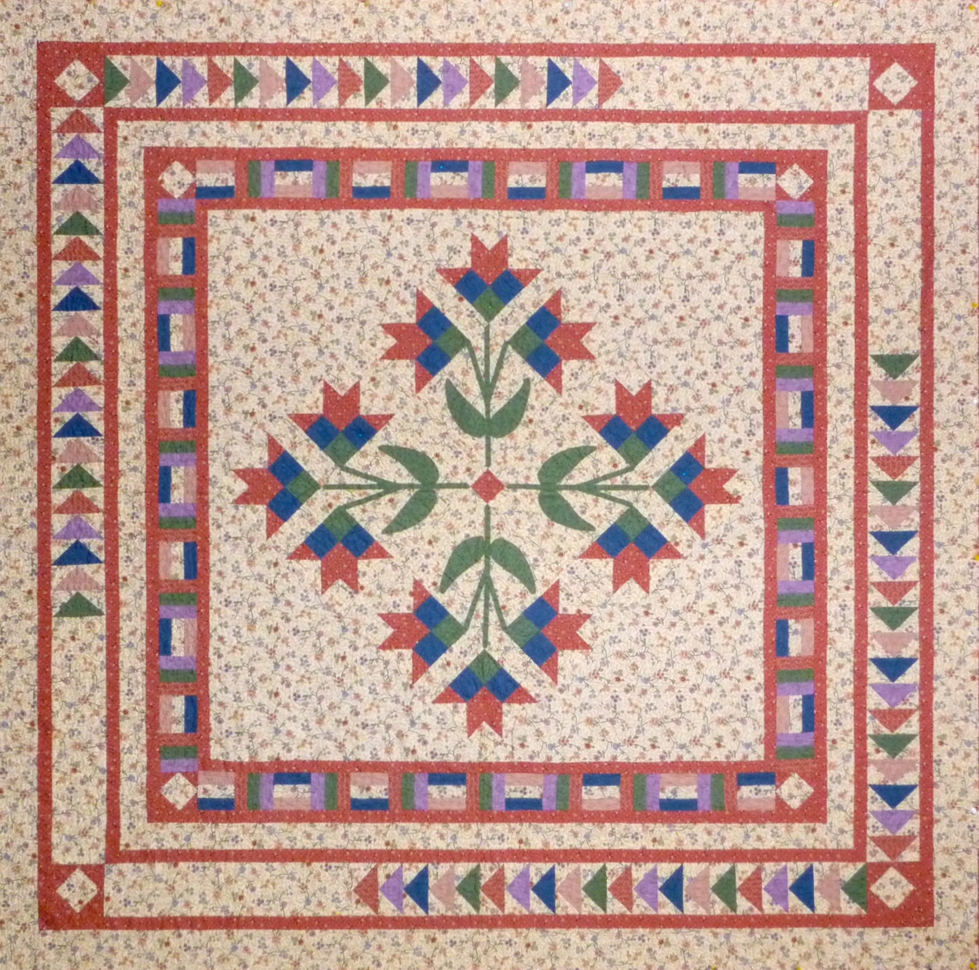 Lilies on the Wing quilt: appliqué lilies in the centre with flying geese borders